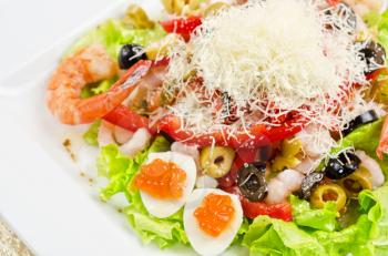 Salad with shrimps, eggs, caviar, calamaries, lettuce, olive, tomato and mozzarella