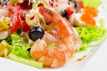 Salad with shrimps, caviar, calamaries, lettuce, olive, tomato and mozzarella