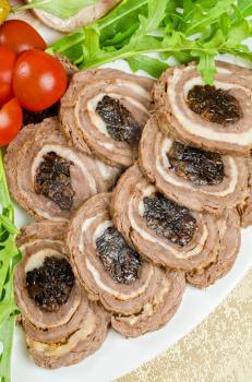 Cutting meat tenderloin with prune with lettuce, tomatoes and Ruccola