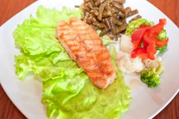 Tasty dish of salmon steak with vegetables