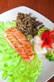 Tasty dish of salmon steak with vegetables