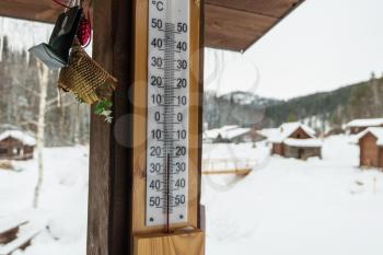 Thermometer on wood house panel in cold winter day. Outdoor thermometer with minus 18 degrees celsius temperature, Altai, Siberia, Russia