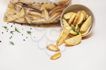 Crisp golden fried french fries potatoes in plate and in pack on color background