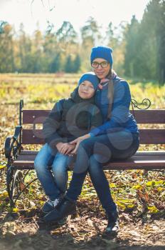 Mother and son at autumn park in sunny beauty day