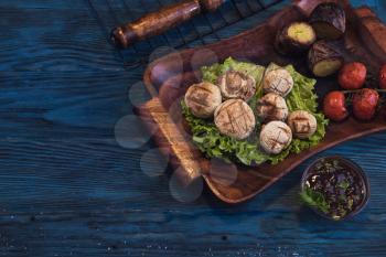 Grilled mushrooms champignons with vegetable on a blue wooden background