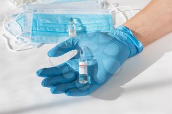 Coronavirus vaccine concept: covid-19 vaccine in hand with blue protective gloves.