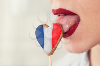 Closeup photo of the woman lips and cookie hearts with flag of France