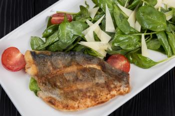 Grilled Dorado fish fillet with spinach, tomato and cheese
