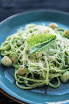 Green Pasta with scallop and sauce on blue plate
