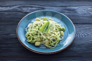 Green Pasta with scallop and sauce on blue plate