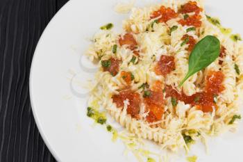 Pasta with parmesan cheese basil and red caviar. The concept of Italian cuisine.