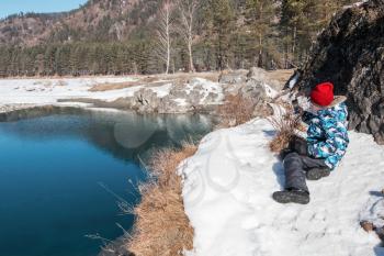 Young boy taking photos on the coast river at beauty sunny spring day, in Altai mountains. Travel vacation concept.