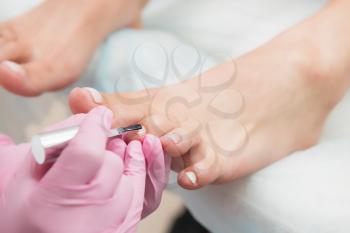 Procedure of pedicure in beauty salon. Nail polishing with nail polish. Closeup photo