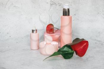 Cosmetic bootles with flowers o n gray background