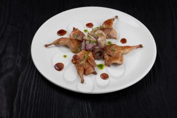 Roasted quails with vegetable on black wooden background with copy space