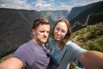 Couple selfie on the top of Altai mountain, Katu Yaryk mountain pass and the valley of the river of Chulyshman, beauty summer day landcape. Travel, leisure and freedom concept