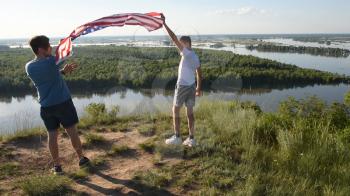 Cute young boy and his father holding aloft the American flag in a patriotic gesture