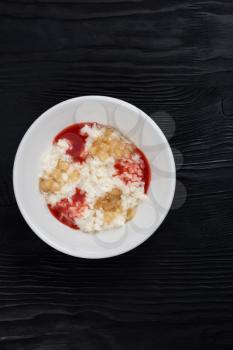 Rice milk porridge with strawberry jam and apple jam in white plate on black wooden background