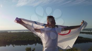 BARNAUL CITY. RUSSIA - JUNE 08, 2021: Boy waving flag the Olympic Games outdoors over cloudy sunset sky. Children sports fan. Summer olympic games on June 08, 2021 in Altayskiy krai, Siberia, Barnaul, Russia