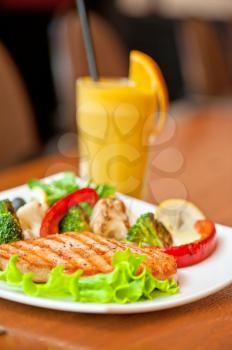 Tasty dish of salmon steak with vegetables and juice
