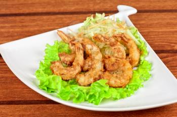 Fried shrimps with lettuce at white plate