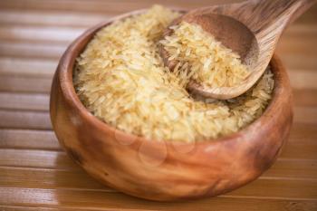 golden rice on wooden plate on wooden background