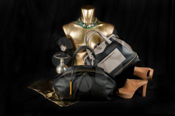 Fashionable handbag  with jewelry and different items for composition on black background. 