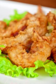 Fried shrimps with lettuce at white plate