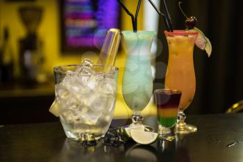 Glasses of different cocktails on bar background