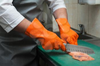 Chef cutting salmon fish on fillet with knife