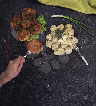 Fried cutlets and russian pelmeni on black background. Food set. Top view.