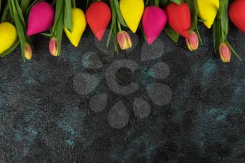 Handmade and real tulips on darken concrete background for Mother's Day, spring time or Easter theme.