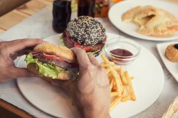 Man eating burgers at table, pov view