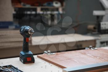 Drill on wooden table in carpenter`s workshop.