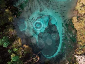 Beautiful Geyser (blue, silver) lake with thermal springs that periodically throw blue clay and silt from the ground. Aerial drone view. Aktash, Altai mountains, Russia