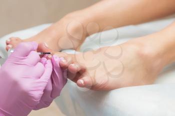Procedure of pedicure in beauty salon. Nail polishing with nail polish. Closeup photo