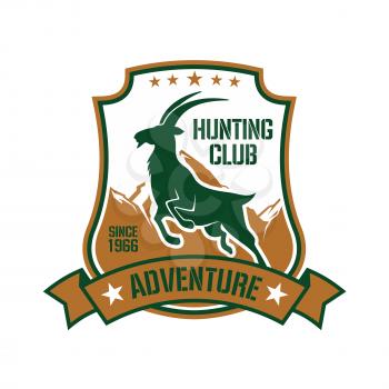 Hunting badge shield design with dark green silhouette of jumping wild goat with snowy mountain peaks on the background, ornated by stars and ribbon banner