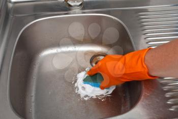 Person cleaning the kitchen sink with a glove 