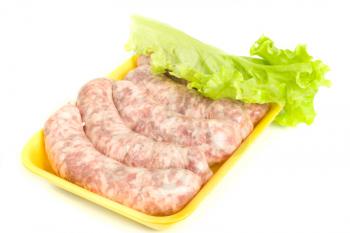 Uncooked Sausages and salad leaf over white