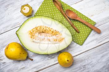 Cut melon with honey and yellow pears on wood in rustic style