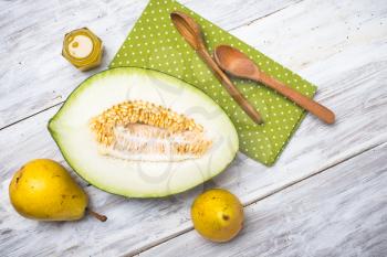 tasty melon with honey and yellow pears on white wood in rustic style