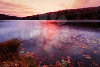 Fall landscape with the forest lake at sunset.