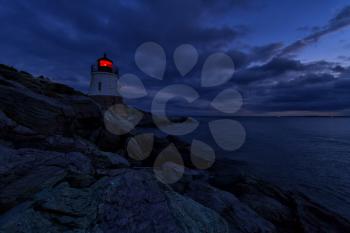 Lighthouse on a rocky shore at sunset.