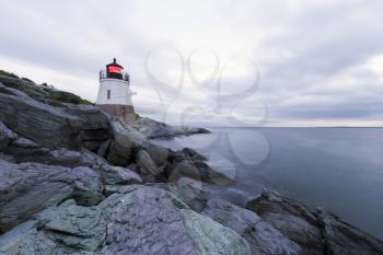 Lighthouse on a rocky shore at sunset.