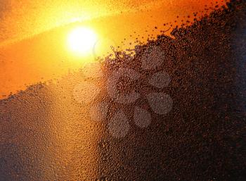 Nature background with bright sunlight, water drops and ice pattern on winter window glass