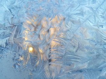 Texture of natural ice pattern and sunlight on winter glass