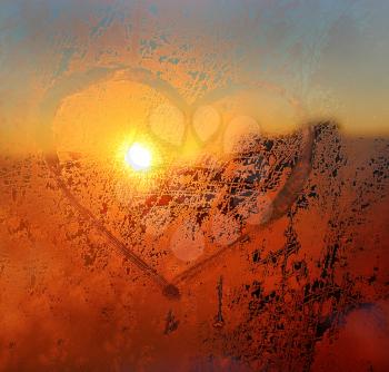 Love symbol drawn on the frozen winter window