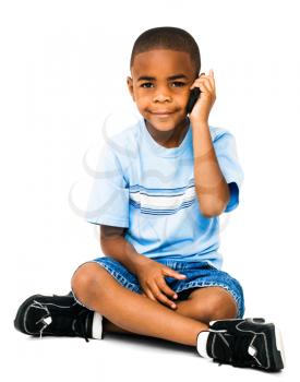 Royalty Free Photo of a Young Boy Sitting Down Talking on a Cell Phone