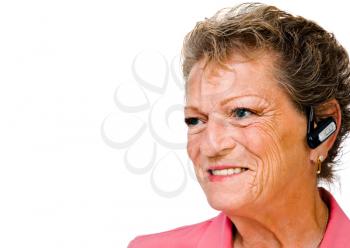 Smiling senior woman wearing a bluetooth isolated over white