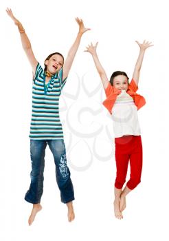Two girls jumping and smiling isolated over white